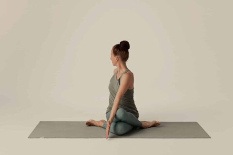 Sarah Della Pietra macht Yoga-Drehung auf grauer Matte