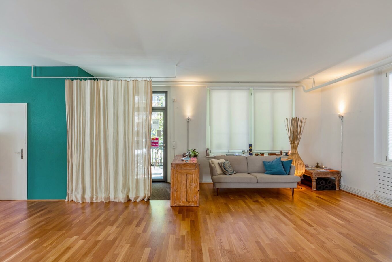 Heller Yoga-Raum mit Parkettboden und Sofa.